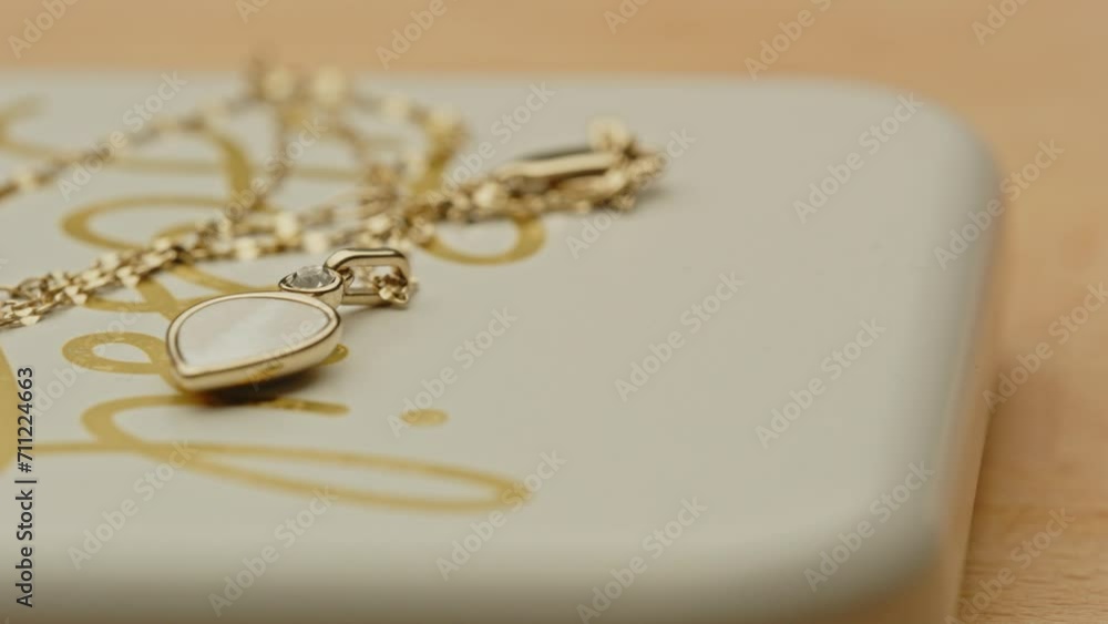 Pan past a beautiful golden necklace with a stunning locket on the lid of a jewelry box Pan past a beautiful golden necklace with a stunning locket on the lid of a jewelry box