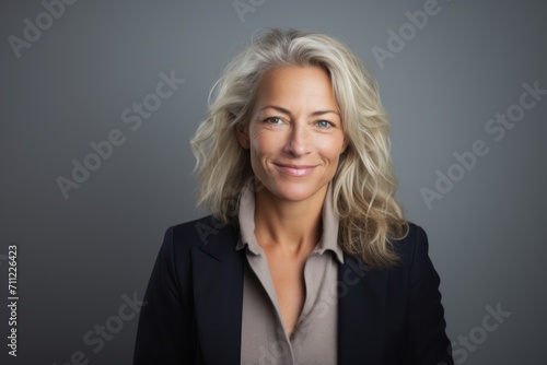 Portrait of a smiling mature businesswoman with wavy blond hair.