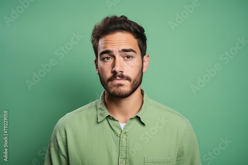 Portrait of a handsome young man in shirt looking at camera isolated over green background