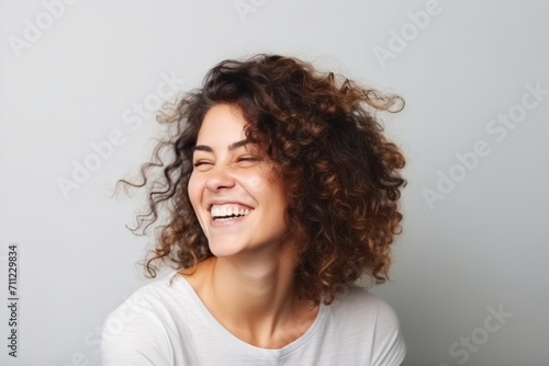 Portrait of a happy young woman with curly hair over gray background