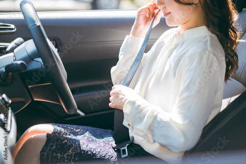 車に乗り込みシートベルトをする女性ドライバー（交通ルール・安全運転・交通安全） 