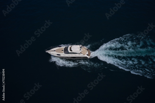 A large white yacht moves on blue water, side view, top view. White yacht moving on the water making a white trail looking like air. © Berg
