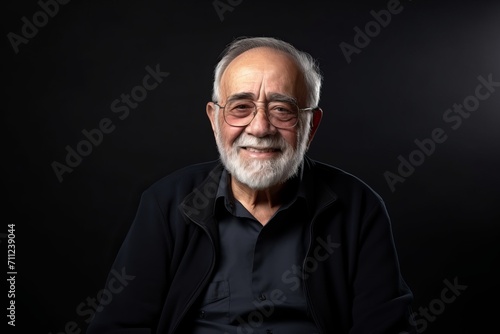 Portrait of an old man with gray beard and glasses on a black background