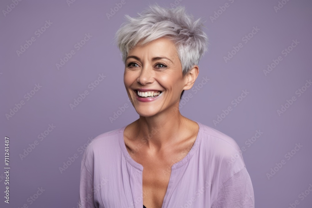 Cheerful mature woman with short grey hair. Beautiful mature woman looking at camera and smiling while standing against purple background Cheerful mature woman with short grey hair. Beautiful mature woman looking at camera and smiling while standing against purple background