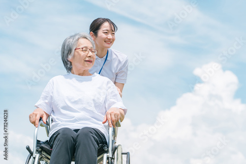 青空と介護福祉士・介護士と高齢者・シニア女性・おばあちゃん
