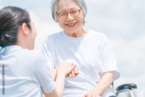 青空と手を合わせる高齢者・シニア女性・おばあちゃんと介護福祉士・介護士
 photo