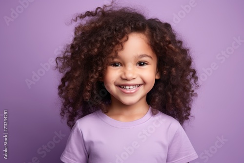 Portrait of a smiling little girl with curly hair against purple background © Inigo