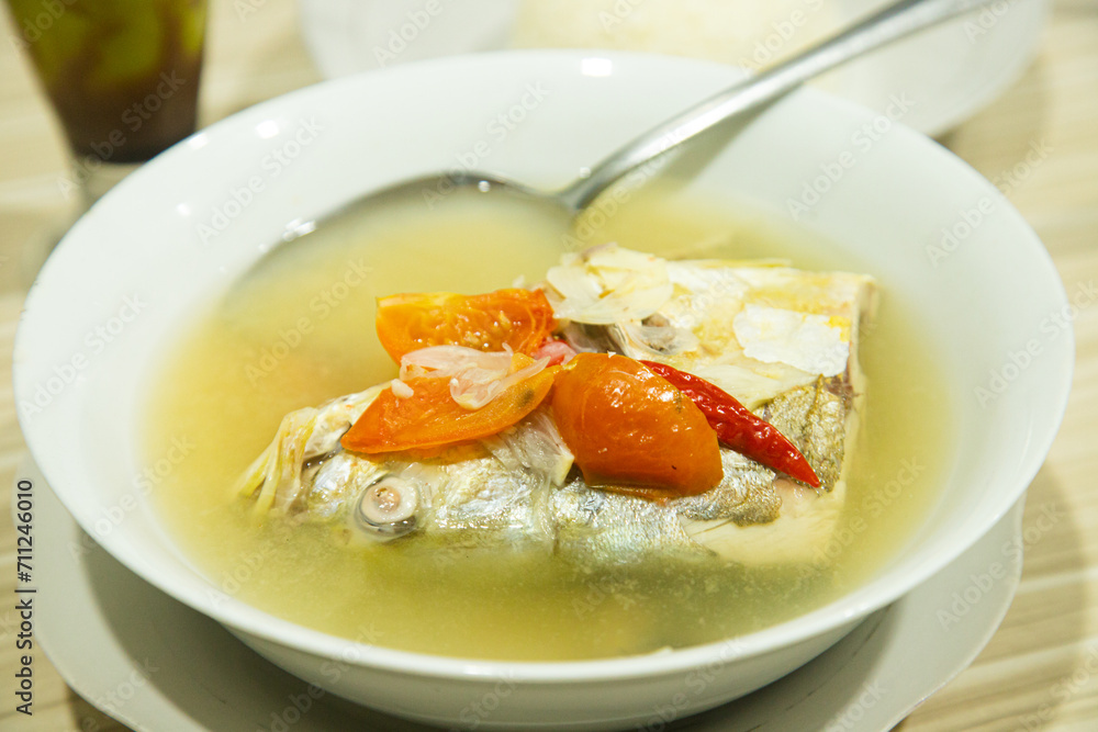 Fresh and delicious cooked fish in yellow sauce served in a white bowl Fresh and delicious cooked fish in yellow sauce served in a white bowl