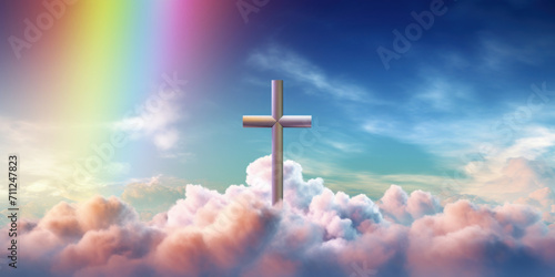 A metallic cross stands prominently against a soft cloudy sky with a subtle rainbow, symbolizing hope and faith. © red_orange_stock