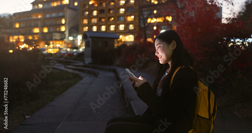 Asian woman, phone and night at city for social media, communication or outdoor networking. Female person relax on mobile smartphone in the late evening for online chatting in urban town of Japan