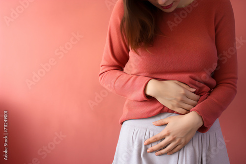 Woman with menstrual cramps clutching stomach in pain in fornt of studio background