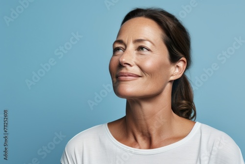 Portrait of happy mature woman looking up over blue background, side view