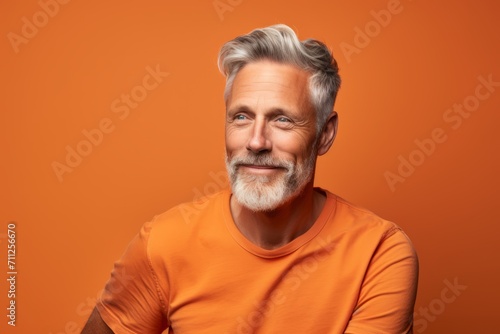 Portrait of handsome senior man in orange t-shirt on orange background