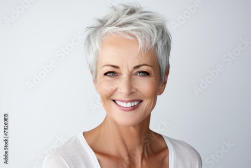 Portrait of happy mature woman with short white hair against grey background