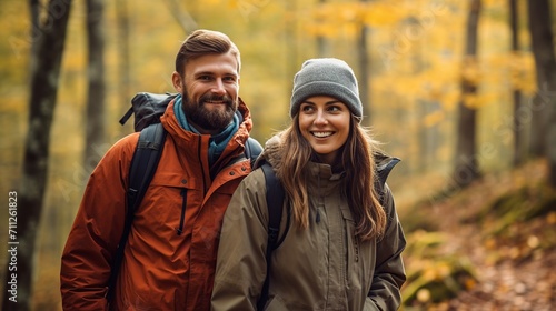 Happy couple hiking in autumn forest with colorful foliage and backpacks
