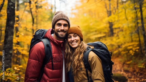 Happy couple hiking in autumn forest with colorful foliage and backpacks