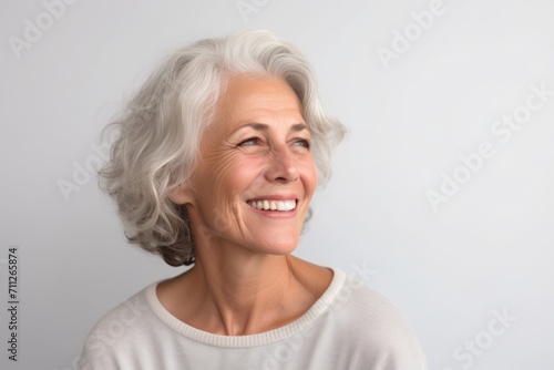 Portrait of a smiling senior woman on grey background. Copy space