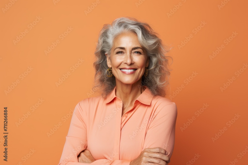 Portrait of smiling senior woman with crossed arms, isolated on orange background Portrait of smiling senior woman with crossed arms, isolated on orange background