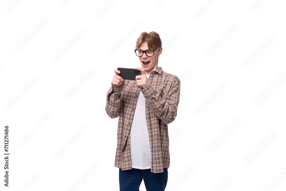 young handsome red-haired guy in a plaid shirt plays on the phone young handsome red-haired guy in a plaid shirt plays on the phone