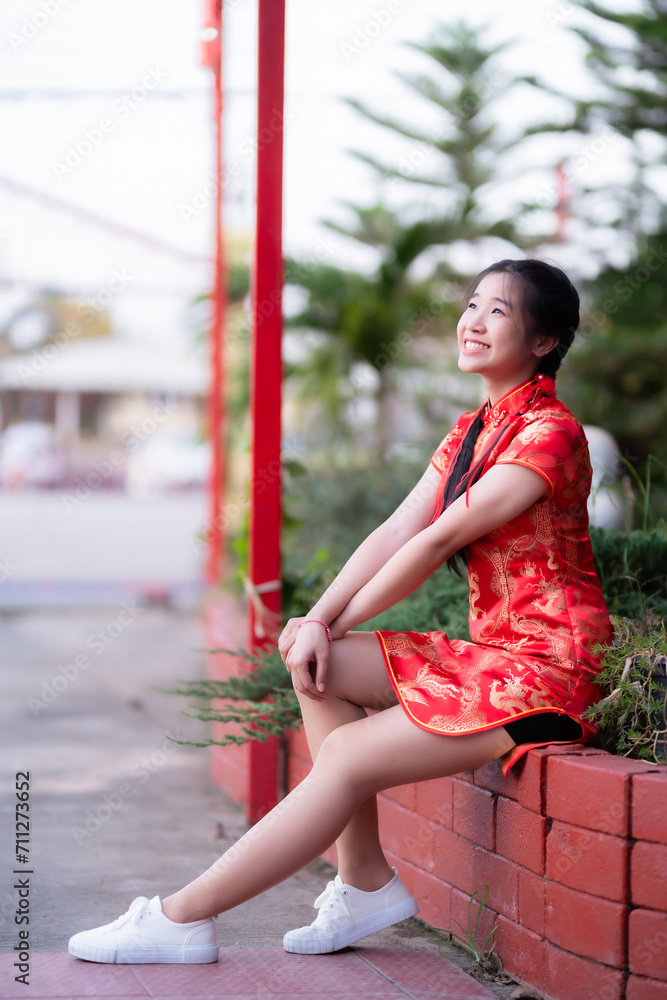 Portrait beautiful cute smiles Asian young woman wearing red cheongsam dress traditional decoration for Chinese new year festival celebrate culture of china at Chinese shrine Public places in Thailand