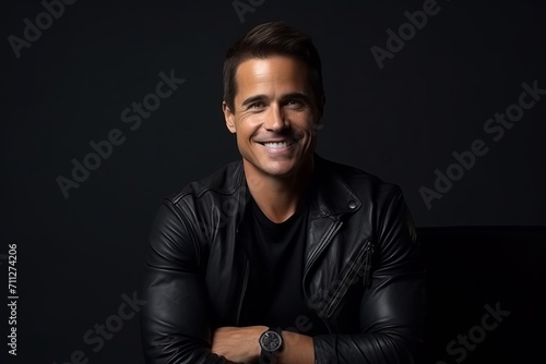 Portrait of a handsome young man in leather jacket, smiling at the camera.