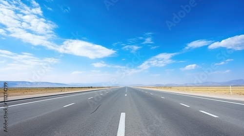 highway in the grassland background of blue sky and bright clouds, long road stretches into the distance. empty street on a beautiful sunny day