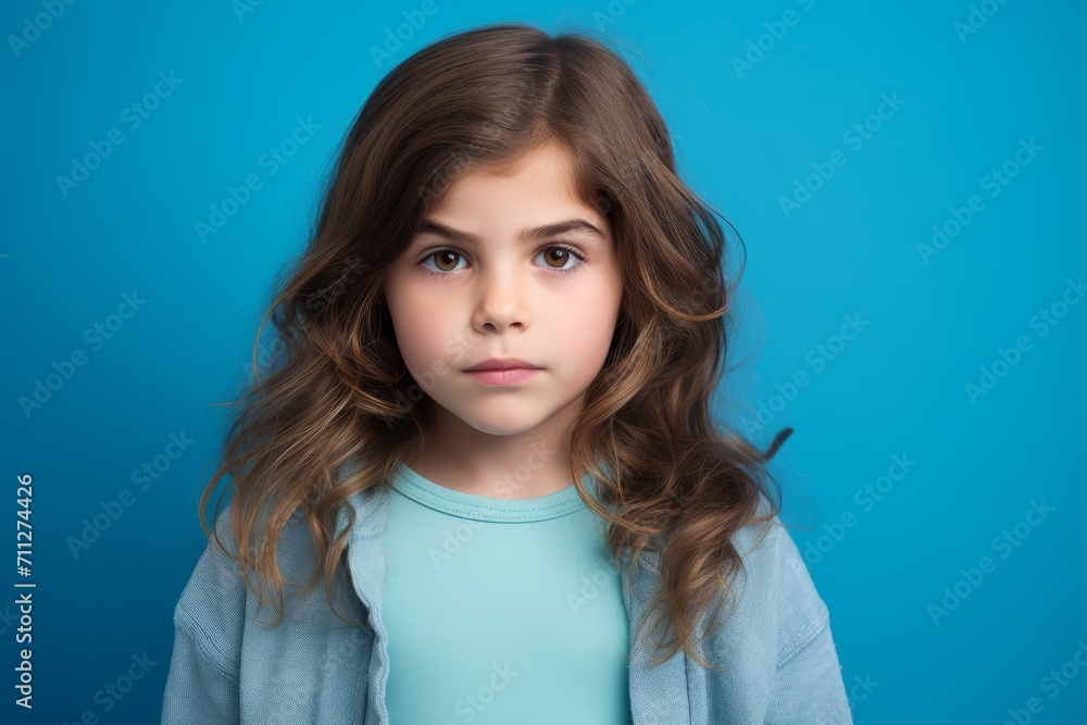 Portrait of a cute little girl with long brown curly hair on blue background Portrait of a cute little girl with long brown curly hair on blue background
