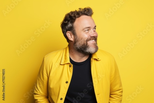 Portrait of a handsome bearded man in yellow jacket on yellow background © Inigo