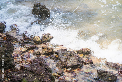 Sea waves hit the rocks hit by sunlight.