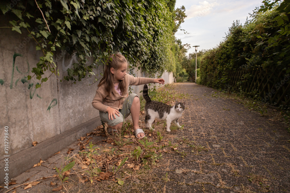 Obraz premium Teen girl plays with a cat, outdoors, village