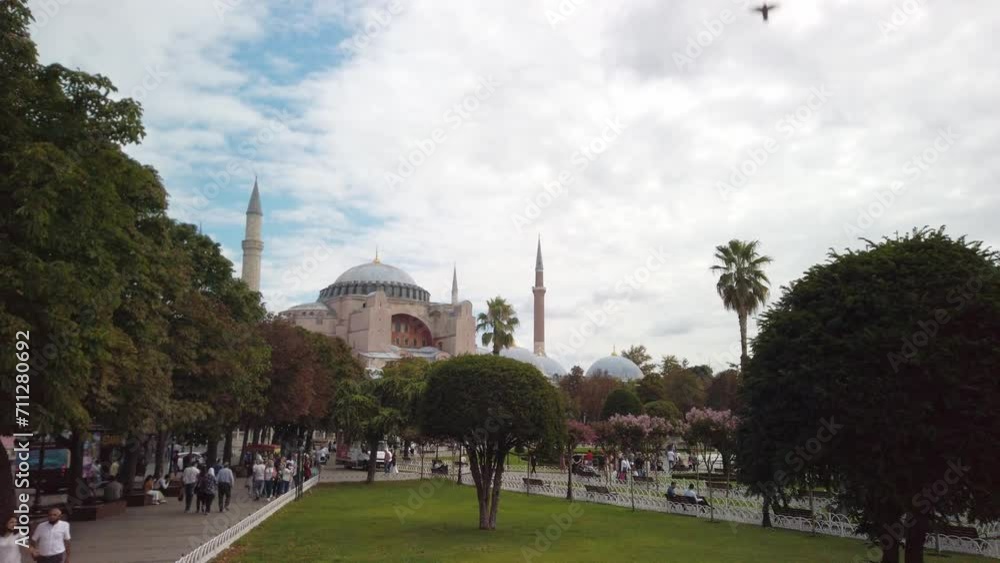 Daytime cinematic slow-mo aerial shot from high above Istanbul's Sultanahmet Park, focusing on Hagia Sophia. Tourists walking around, birds soaring in the sky. Daytime cinematic slow-mo aerial shot from high above Istanbul's Sultanahmet Park, focusing on Hagia Sophia. Tourists walking around, birds soaring in the sky.