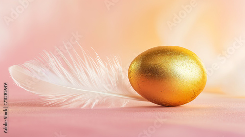 A golden egg resting gently beside a delicate white feather on a soft pink background symbolizing luxury or Easter celebration