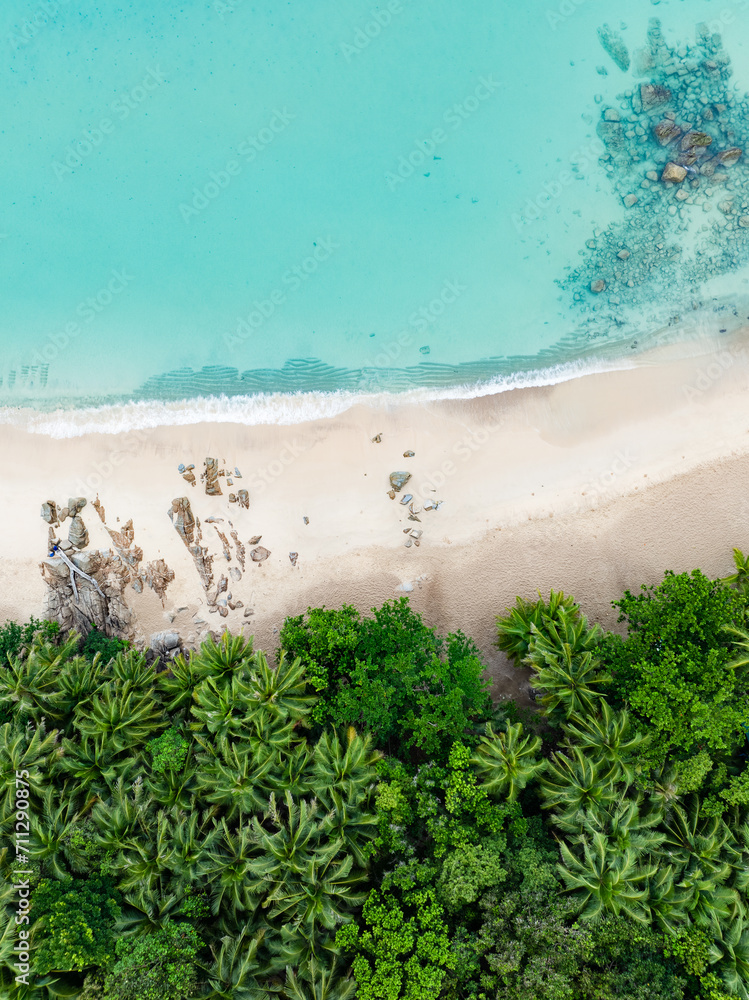 View from above, stunning aerial view of Banana beach, a beautiful white sand beach surrounded by palm trees and bathed by a turquoise water. Phuket, Thailand.