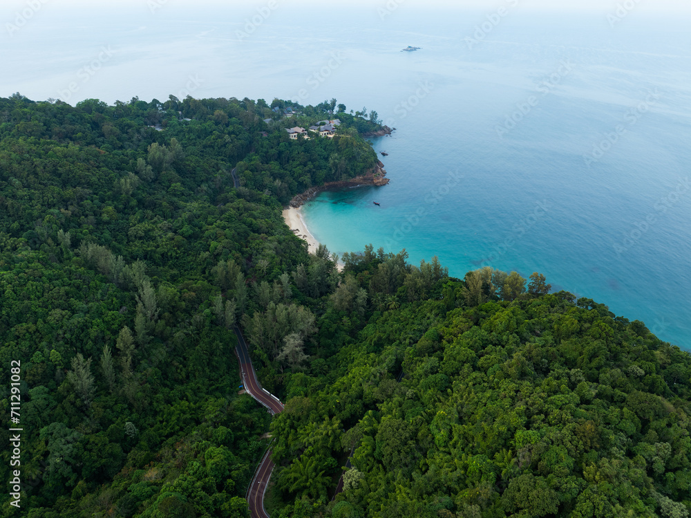 View from above, stunning aerial view of Banana beach, a beautiful white sand beach surrounded by palm trees and bathed by a turquoise water. Phuket, Thailand.
