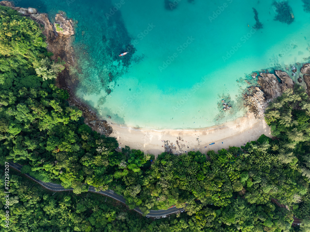 View from above, stunning aerial view of Banana beach, a beautiful white sand beach surrounded by palm trees and bathed by a turquoise water. Phuket, Thailand.
