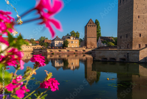 Strasbourg, France. View of Ponts Couverts de Strasbourg (Covered Bridges of Strasbourg) with bright flowers in the foreground. Medieval bridge over the river Ill. photo