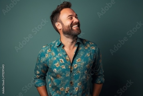 Portrait of a handsome man laughing with closed eyes on blue background