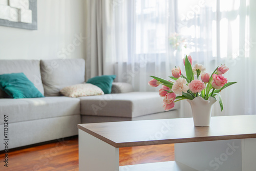 pink spring flowers in white ceramic vase in modern home interior