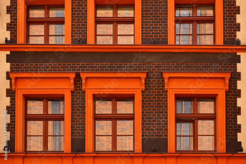 Facade of the historic building with windows, orange frames and a brown brick wall. Ancient architecture. Torun, Poland, August 2023 