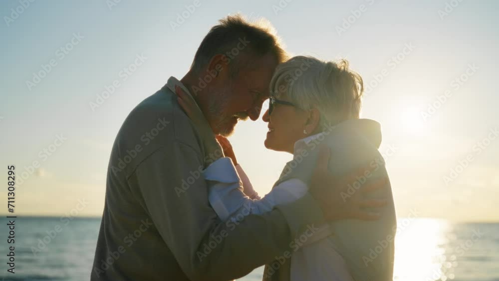 Senior couple man woman hugging admiring sea at sunset in evening, back view. Elderly couple family on date cuddling embracing talking. Lifelong relationships marriage, love enjoy rest concept. Senior couple man woman hugging admiring sea at sunset in evening, back view. Elderly couple family on date cuddling embracing talking. Lifelong relationships marriage, love enjoy rest concept.
