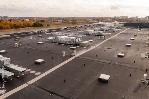 Drone photography of large commercial building rooftop with air conditioning machinery during autumn morning