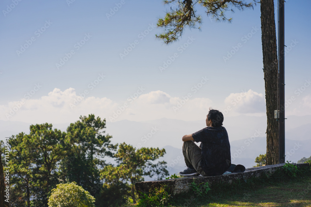 landscape and travel concept with solo freelancer man sit on wooden and use tablet work from outdoor with layer of mountain background