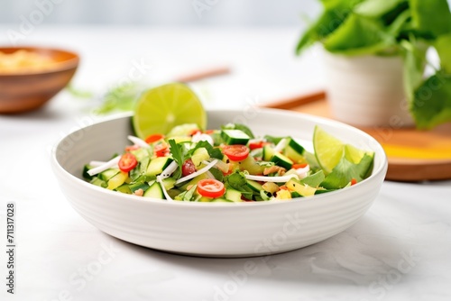 fresh cactus salad in a white bowl with lime wedges on the side