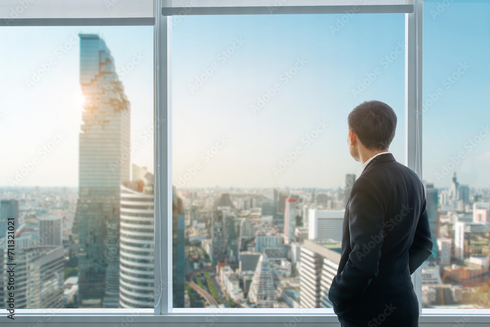 A businessman is observing the future metropolis from the top of an office tower.