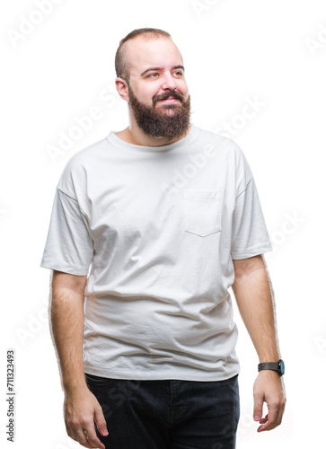 Young caucasian hipster man wearing casual t-shirt over isolated background looking away to side with smile on face, natural expression. Laughing confident.