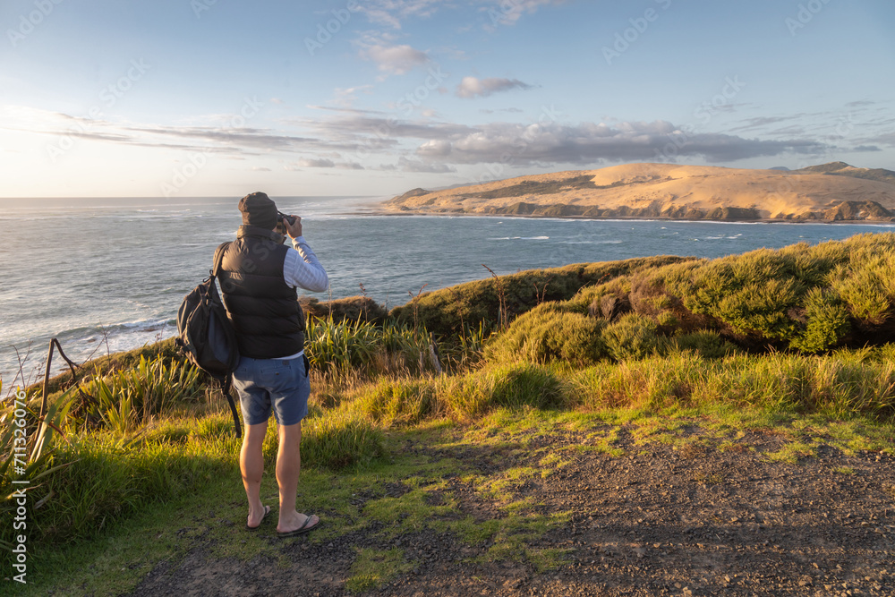 Man taking a photo in the Hokianga Harbour. Opononi, Northland, New Zealand.