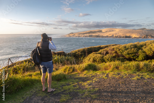 Man taking a photo in the Hokianga Harbour. Opononi, Northland, New Zealand. © Zenstratus