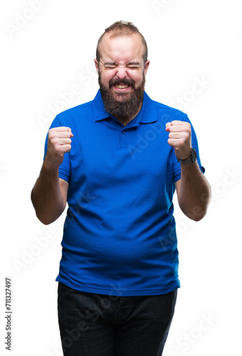 Young caucasian hipster man wearing blue shirt over isolated background excited for success with arms raised celebrating victory smiling. Winner concept.