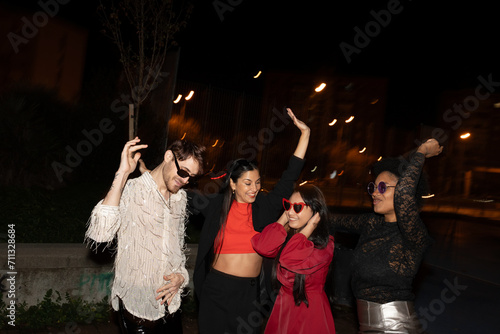 Group of trendy young adults dancing on an urban street at night. 