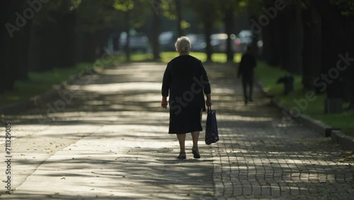 Rear view of an elderly woman walking through a park. A pensioner walks in the park photo